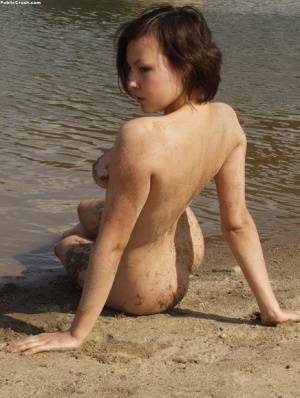 Amateur girl covers her naked body in sand while at a nude beach on fangals.org