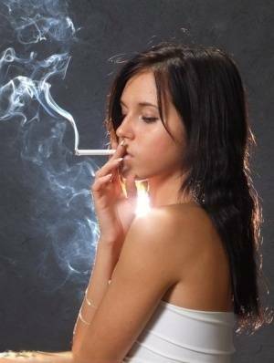 Young brunette smokes a cigarette while wrapped in tight white dress and heels on fangals.org