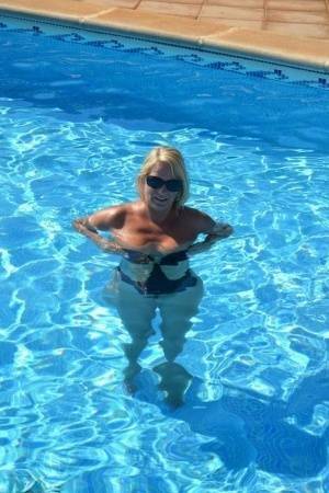 Middle-aged blonde Sweet Susi frees her tits & pussy from a swimsuit by a pool on fangals.org