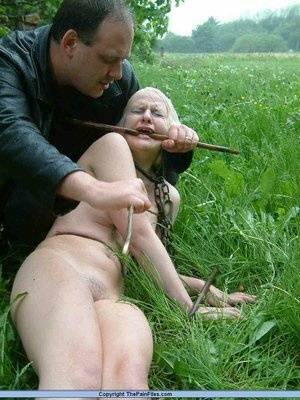 Naked blonde slave is caned and stomped on in a field of lush grass on fangals.org