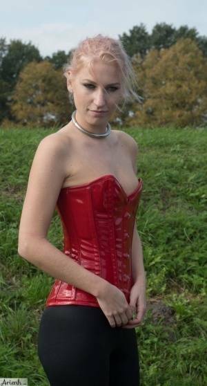 Collared girl Arienh Autumn models a red leather corset while in a field on fangals.org