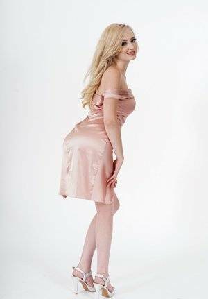 Fair skinned blonde displays her bare legs while posing in a dress and heels on fangals.org