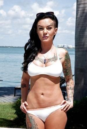 Tattooed whore Lolo Luscious exposing big hooters in swimming pool on fangals.org